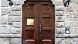 A double wooden door with a plaque, set in a stone wall with a decorative window above. - Relais Stibbert Florence (Florence)