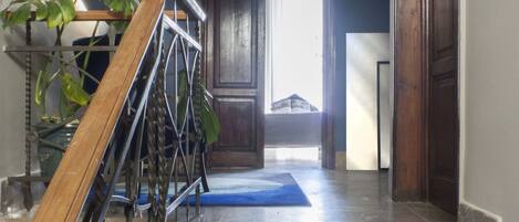 A staircase with a wooden handrail, a potted plant, and a blue mat at the base.