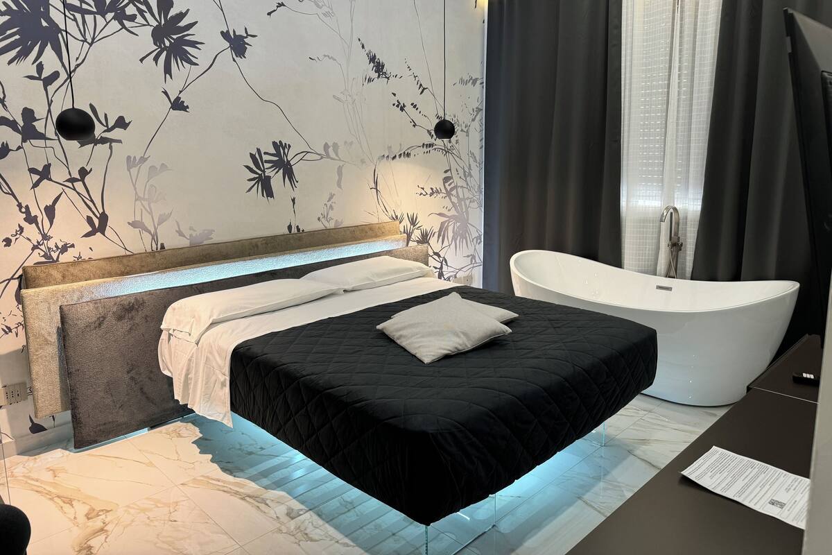Quarto moderno com uma cama grande, banheira integrada e parede com um desenho floral.