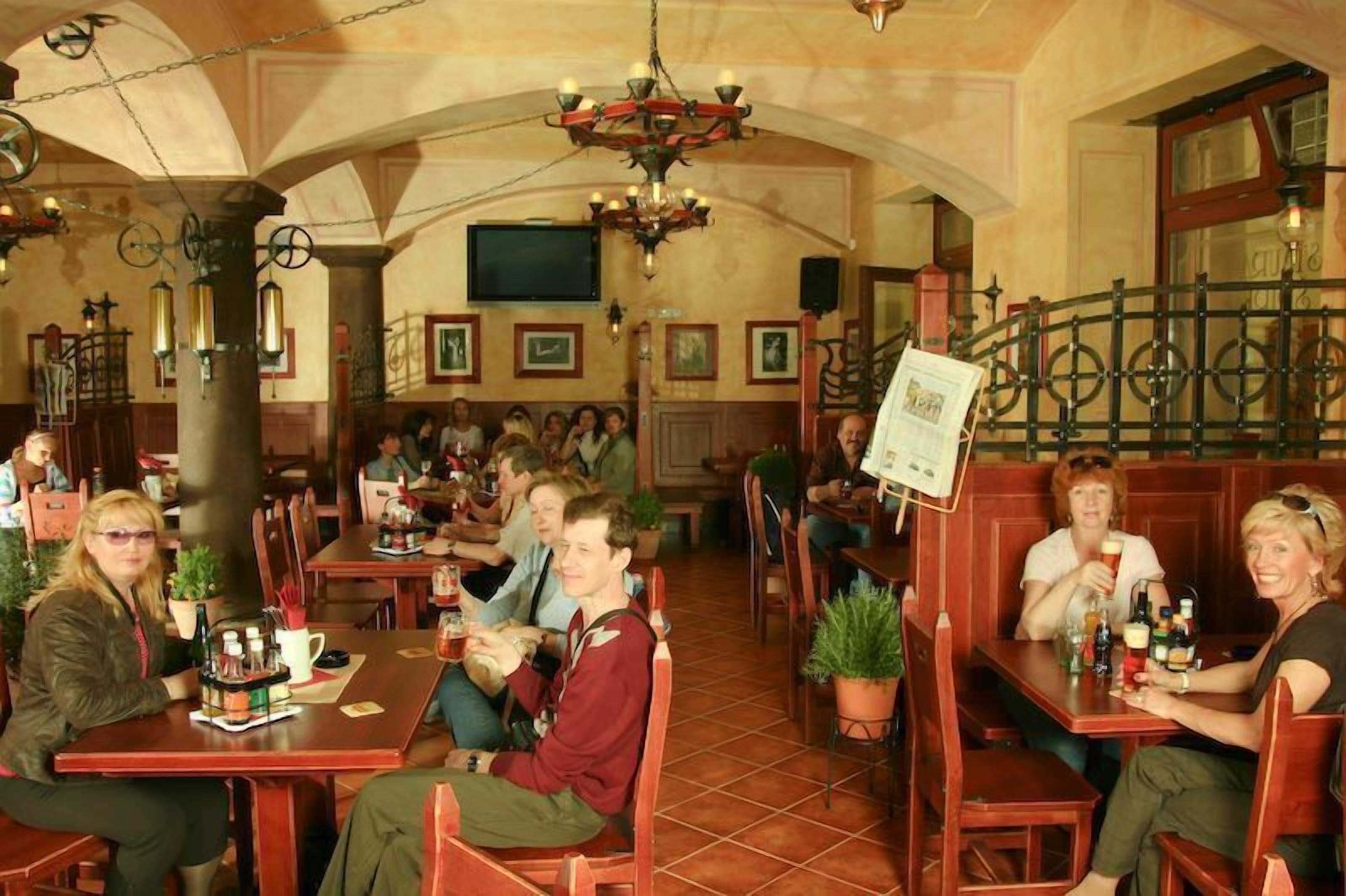 Un restaurant amb taules i caires de fusta, una làmpada penjant i un sòl de rajola.