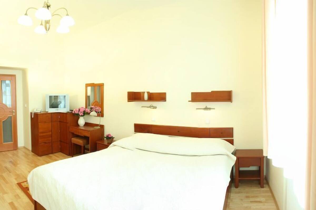 A bedroom with a large bed, wooden dresser, desk, and a mirror.