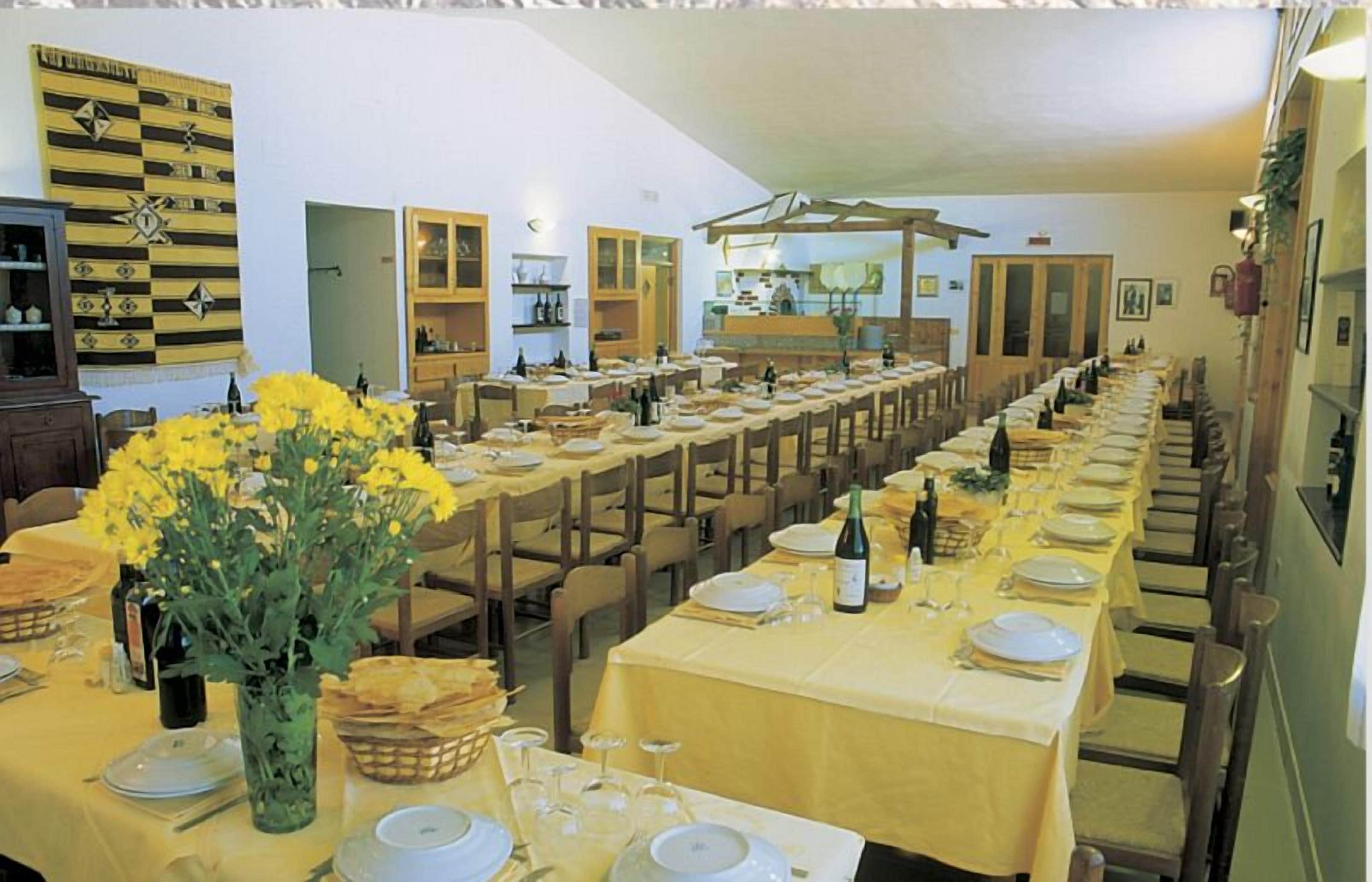 A long dining hall with multiple tables set for a meal, featuring a chessboard on the wall.