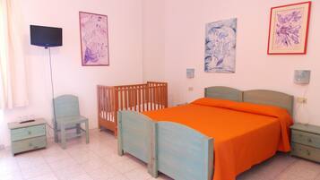 Een slaapkamer met een bed, ledikant, stoel, televisie en kunstwerken aan de muur.