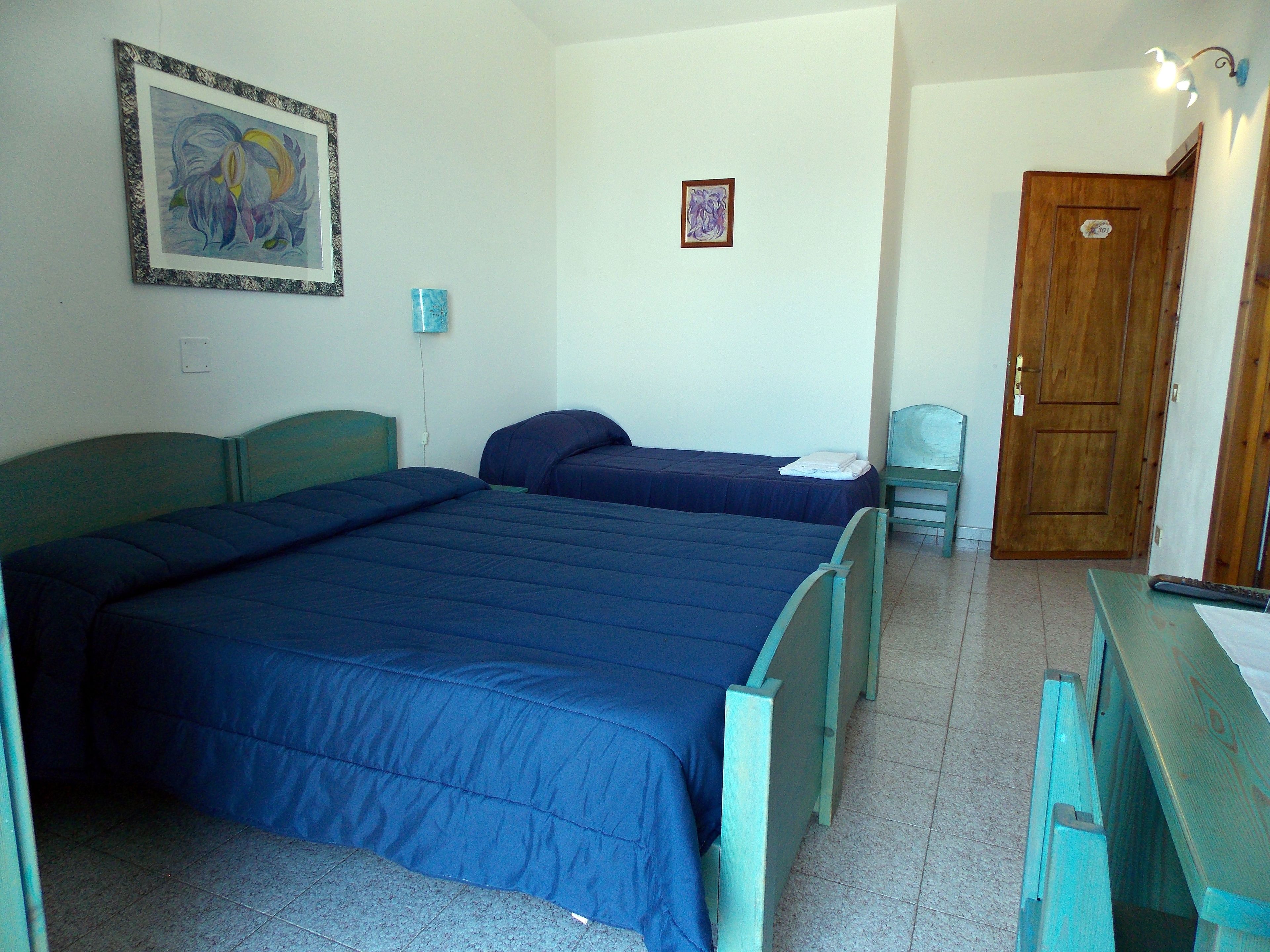 Una camera da letto con due letti, una scrivania, una sedia e una porta.