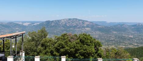 Una terraza con asientos al aire libre y vistas a un paisaje montañoso.