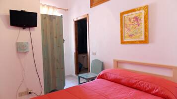 A bedroom with a bed, a television, a chair, and a door.