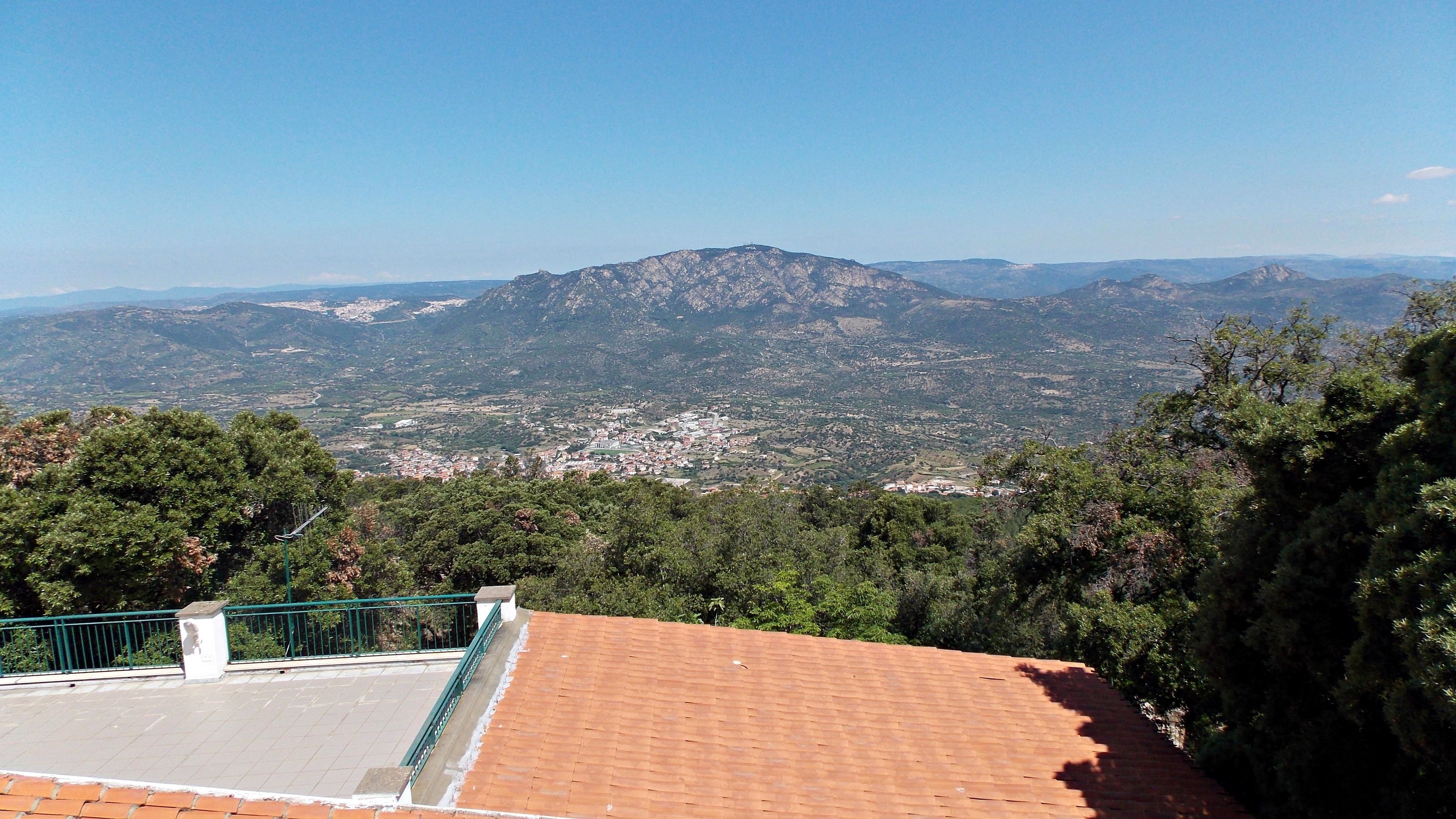 Vista da una terrazza sul tetto su un paesaggio montuoso con una città in basso.