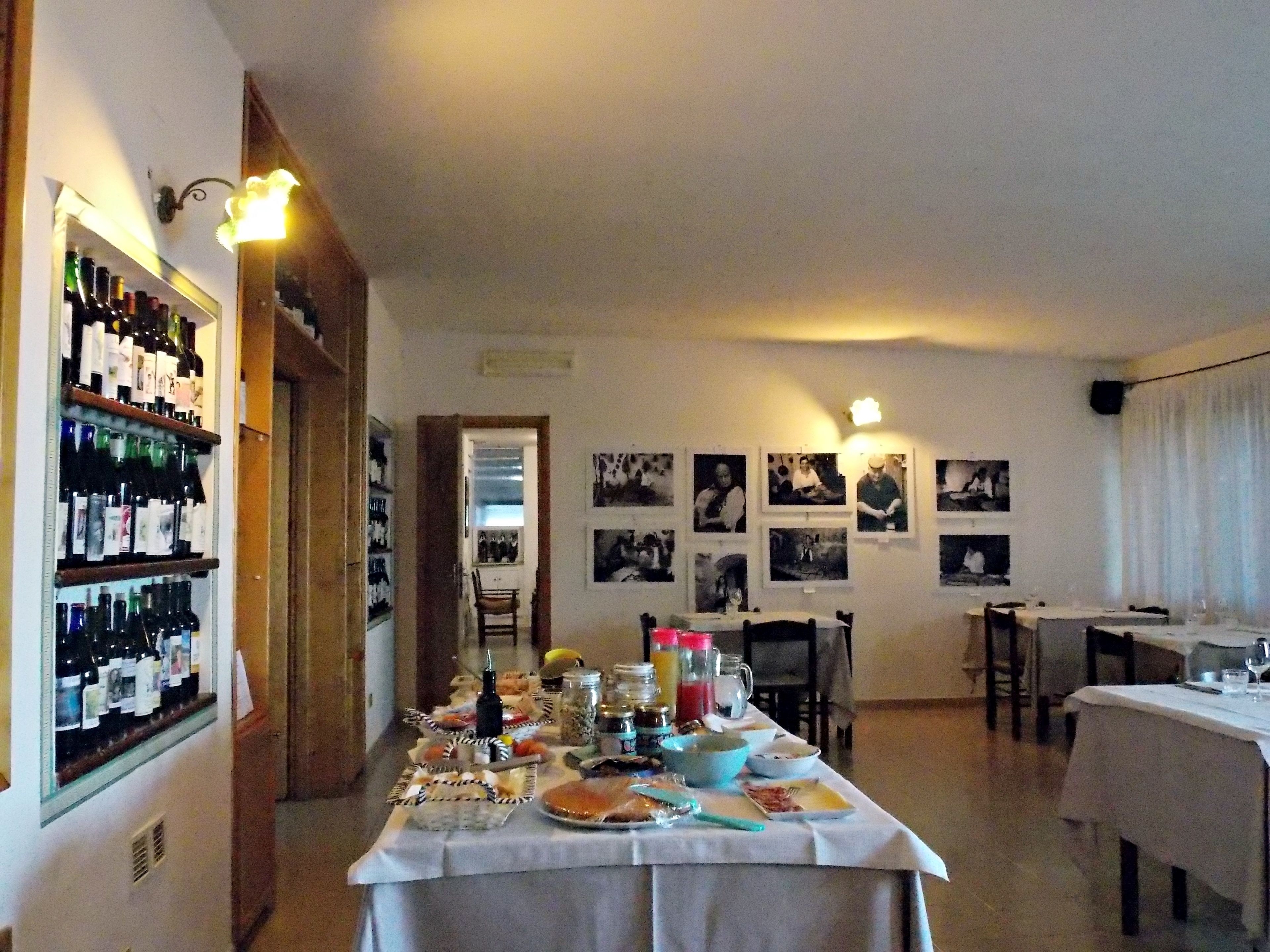 Ein Essbereich mit einem gedecktem Tisch, einem Weinregal und mehreren gerahmten Bildern an der Wand.