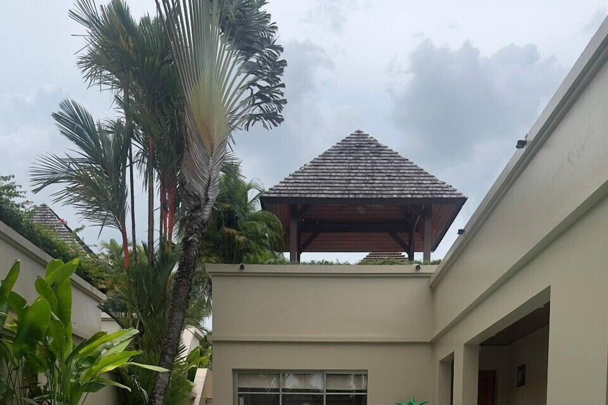 A swimming pool with two inflatable toys, a gazebo, and tropical plants.