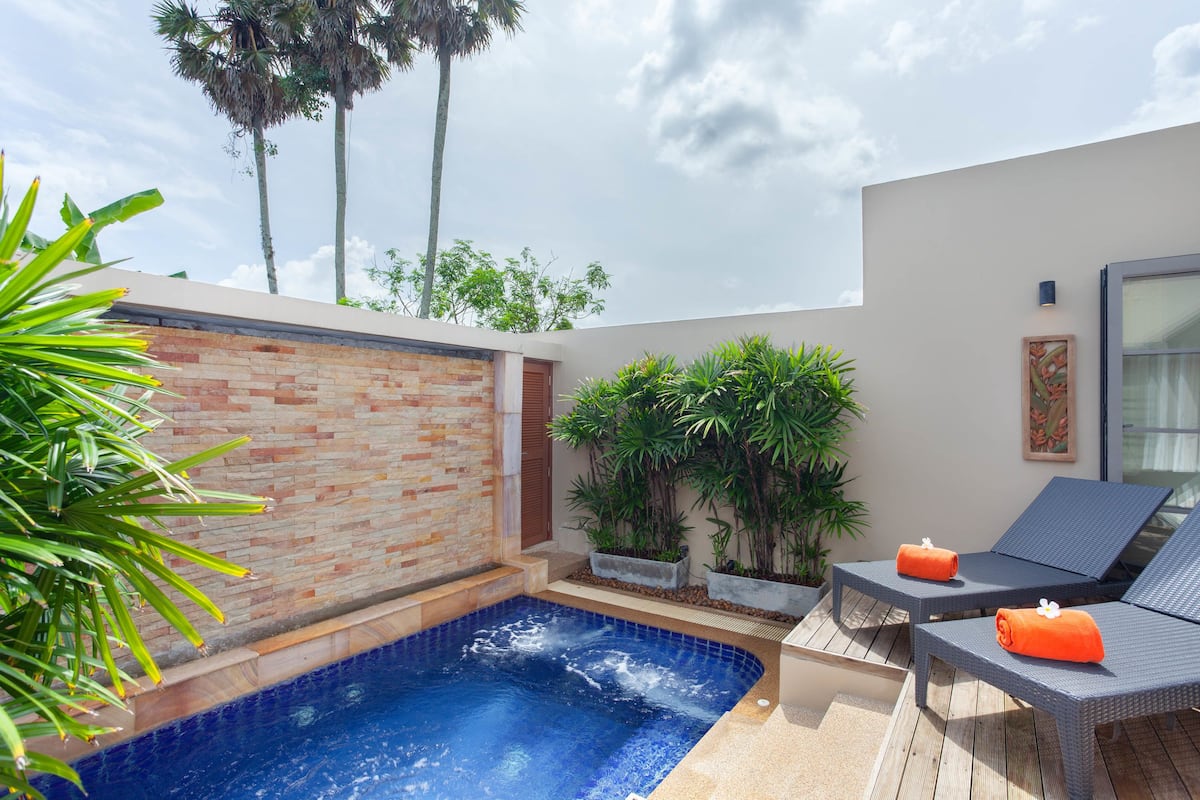 A modern outdoor pool area with a brick wall, lounge chairs, and potted plants.