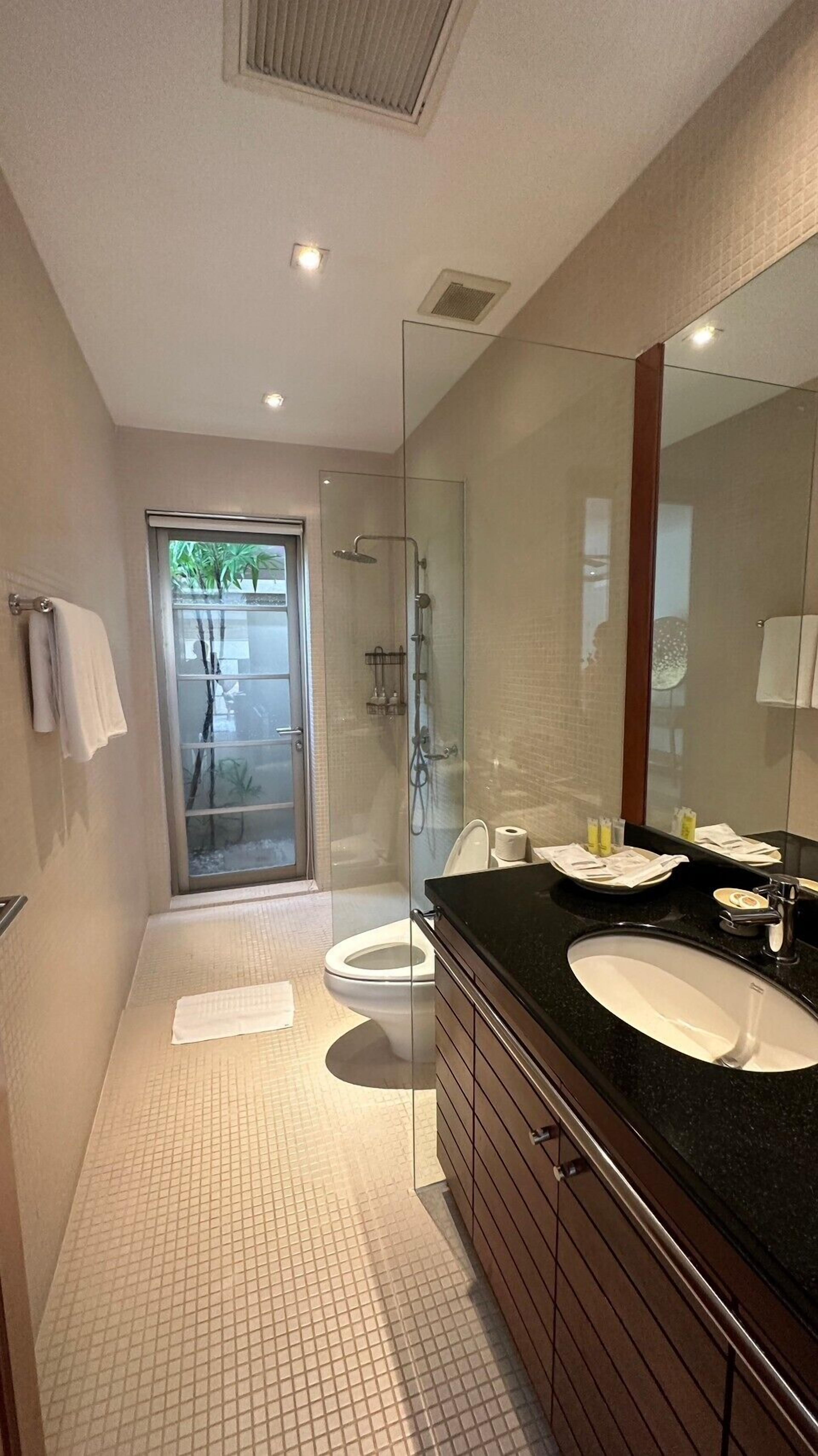 Une salle de bain moderne avec deux lavabos, un grand miroir et une douche à l’italienne.