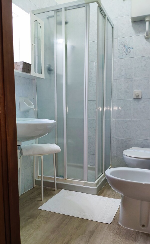 A bathroom with a glass shower enclosure, two sinks, and a toilet.
