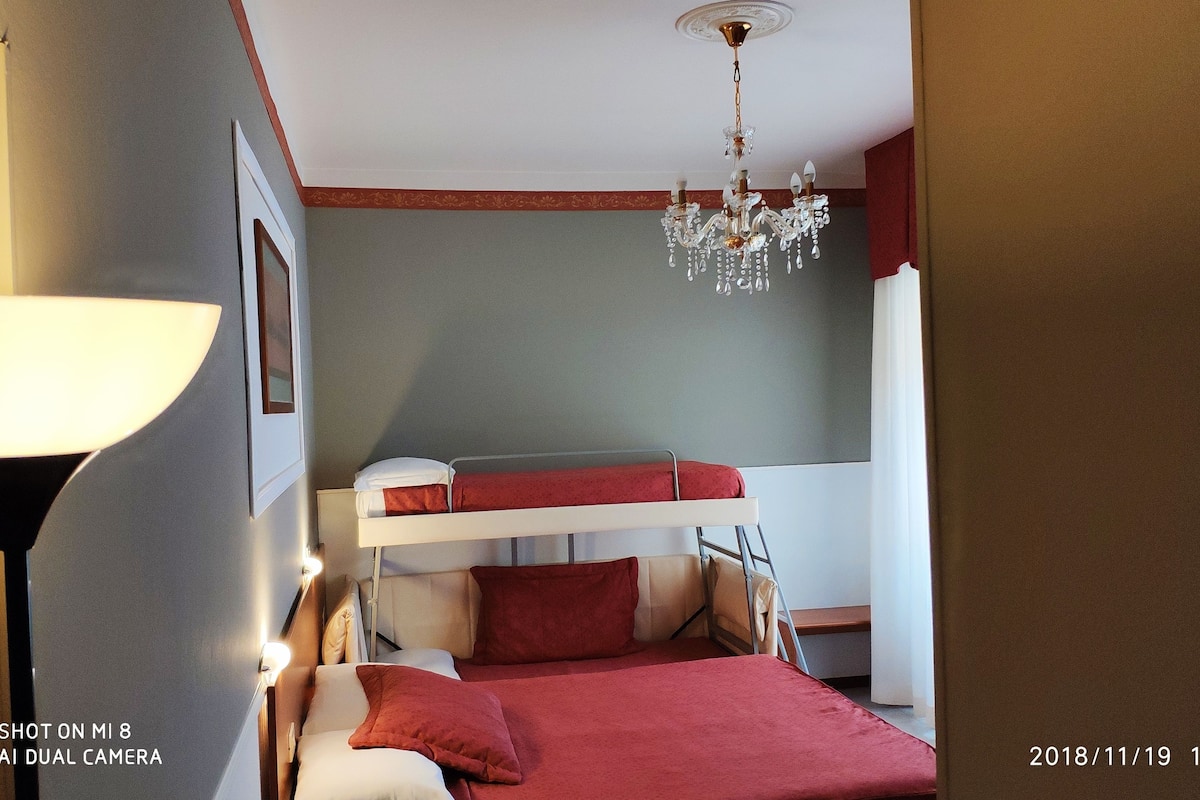 Habitación de hotel con una litera, un candelabro y una lámpara de noche.