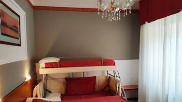 A bunk bed room with a chandelier, a framed picture on the wall, and a window with curtains.