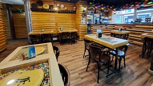 Interior de restaurante con paredes de madera, mesas, sillas, una barra y un ventanal con vistas.