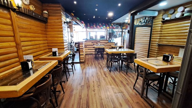 Ein Restaurantinneres mit Holzwänden, Tischen und Stühlen.
