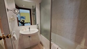 A bathroom with a sink, mirror, toilet, and shower.
