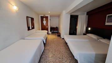 Habitación de hotel con dos camas individuales, una puerta de madera, un escritorio pequeño y un espejo en la pared.