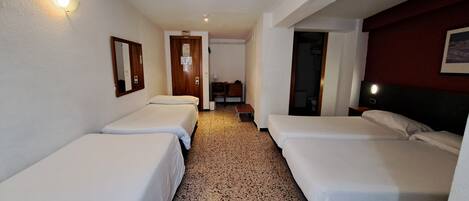 Habitación de hotel con dos camas individuales, una puerta de madera, un escritorio pequeño y un espejo en la pared.