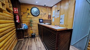 Ein Holzinterieur mit einer Rezeption, einer Wanduhr, einem Feuerlöscher und einem Warnschild.