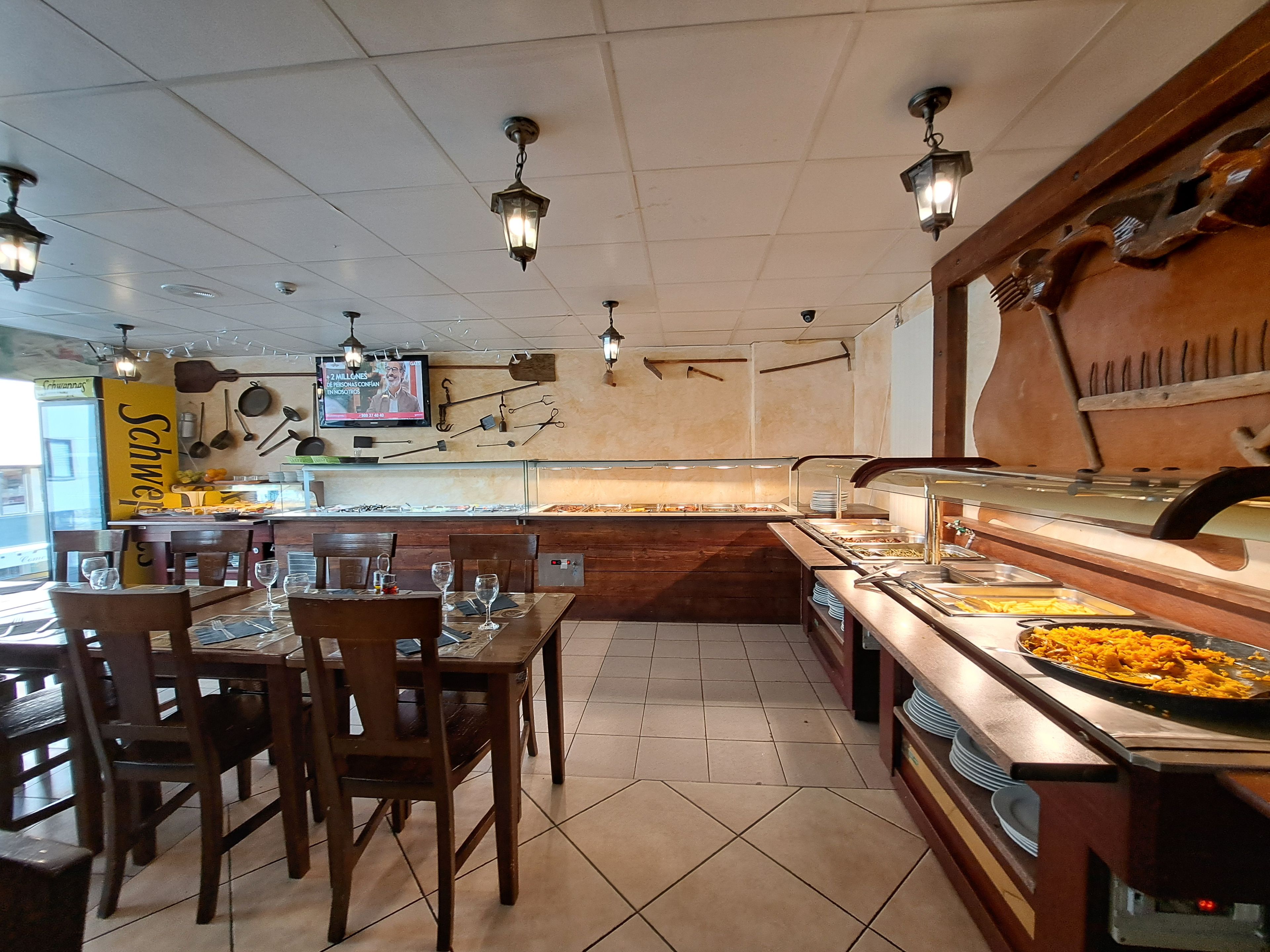 A buffet setup with multiple serving stations, wooden tables, and chairs.