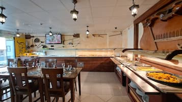 A buffet setup with multiple serving stations, wooden tables, and chairs.