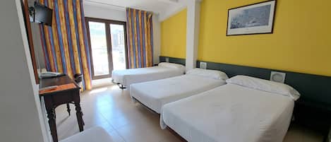 Habitación de hotel con dos camas, un escritorio, una silla, un televisor y una ventana con cortinas.