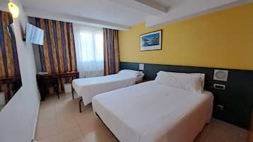 Hotelkamer met twee bedden, een bureau, een stoel, een televisie en een raam met gordijnen.