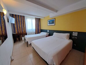 A hotel room with two beds, a desk, a chair, a television, and a window with curtains. - Cims (Pas de la Casa)