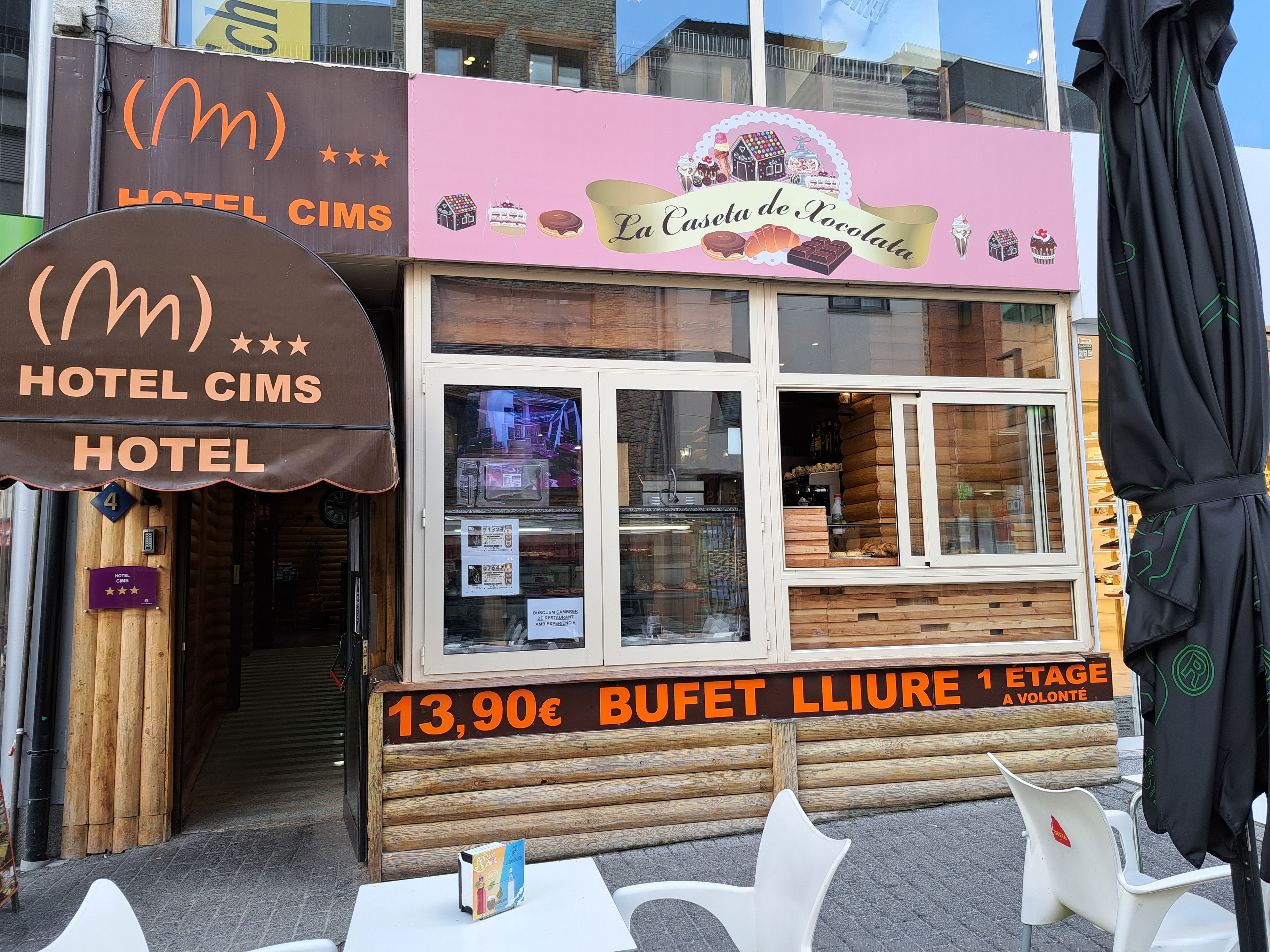 Hotel anomenat 'HOTEL CIMS' amb un cartell que indica el preu de menjar a forfet a 13,90€.