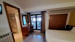 Ein Hotelzimmer mit Bett, Schreibtisch, Stuhl, Kleiderschrank und Blick ins Freie.
