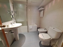 Un baño con lavamanos, inodoro, bidé y cabina de ducha de vidrio.