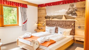 A wooden bed with white linens, a red curtain, and a wall mural. - Hotel und Restaurant Köhlerhütte (Gruenhain-Beierfeld)