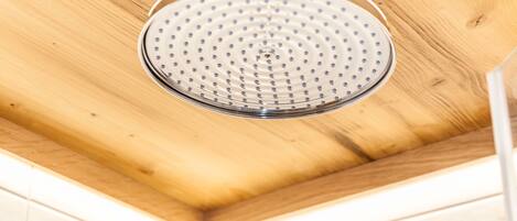 Un cabezal de ducha con diseño circular, sujeto a un techo de madera.