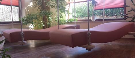 Una habitación con suelo de madera, sofá rosa y una silla mecedora.