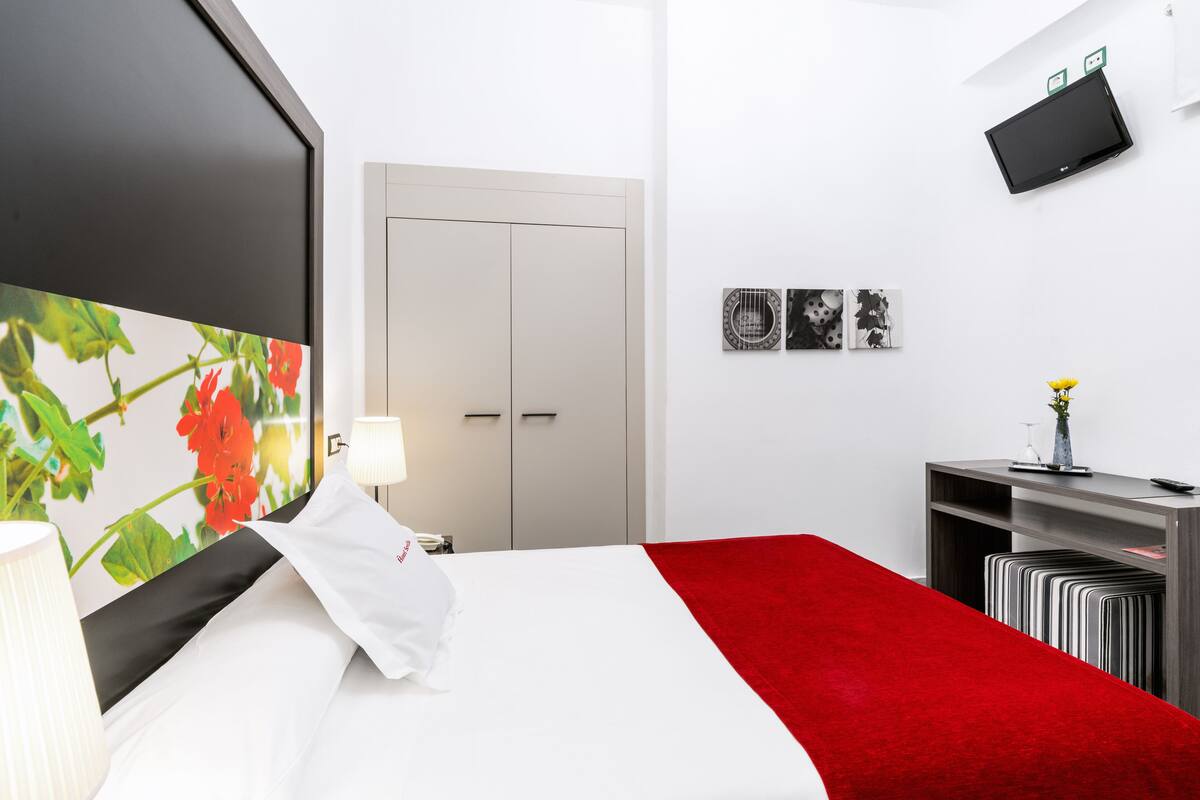 Ein Hotelzimmer mit Bett, Schreibtisch, Fernseher und einer Tür.