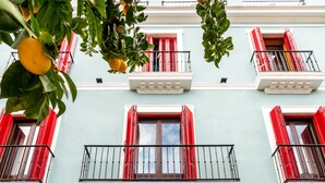 A building facade with a large wooden door, red shutters, and a balcony with a metal railing.