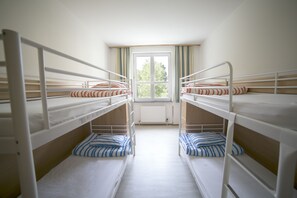 A room with bunk beds, a window with curtains, and a radiator. - Muffin Hostel (Salzburg)