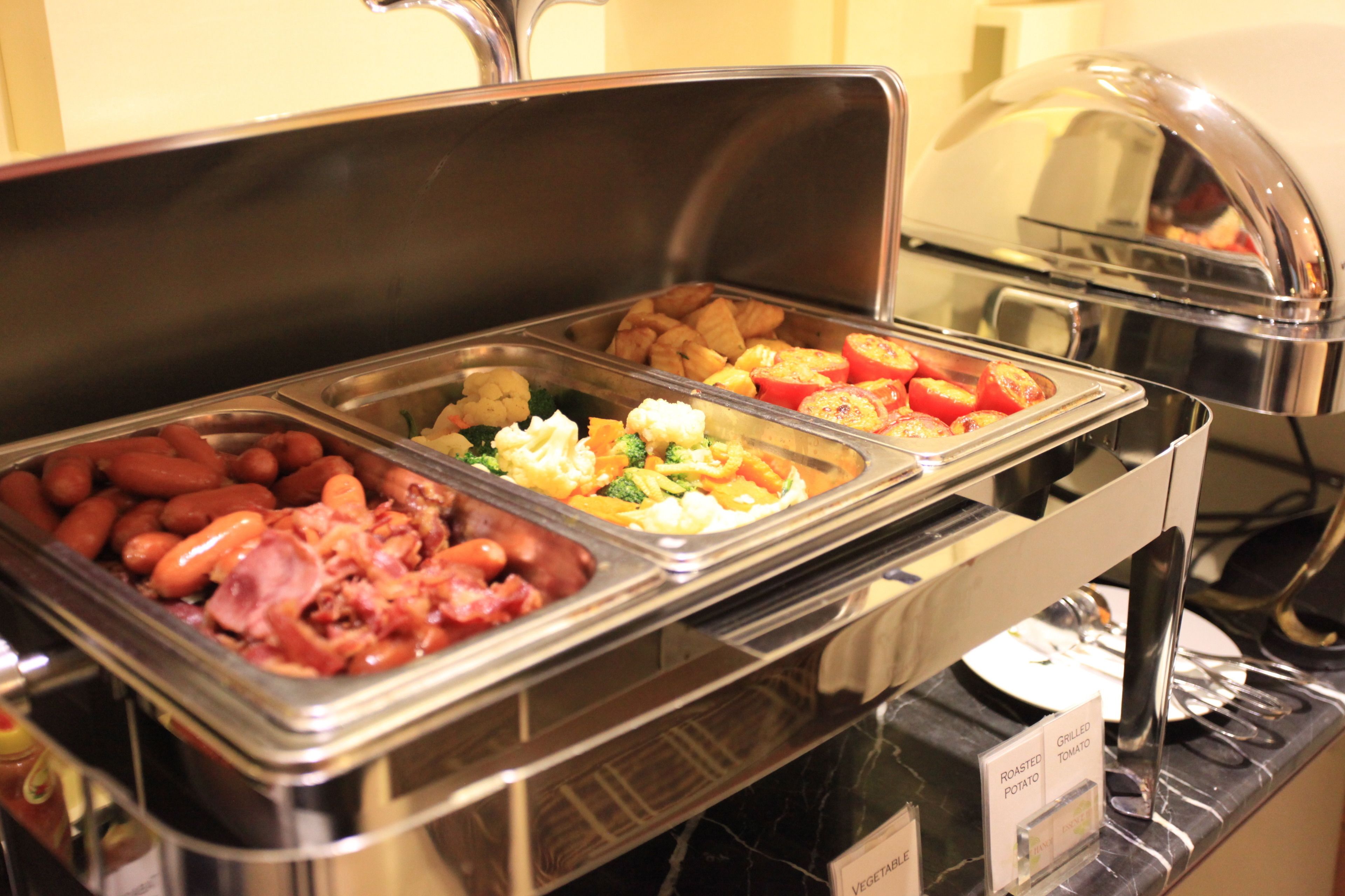 Un buffet proposant une variété de plats, notamment des haricots, des légumes et des viandes.