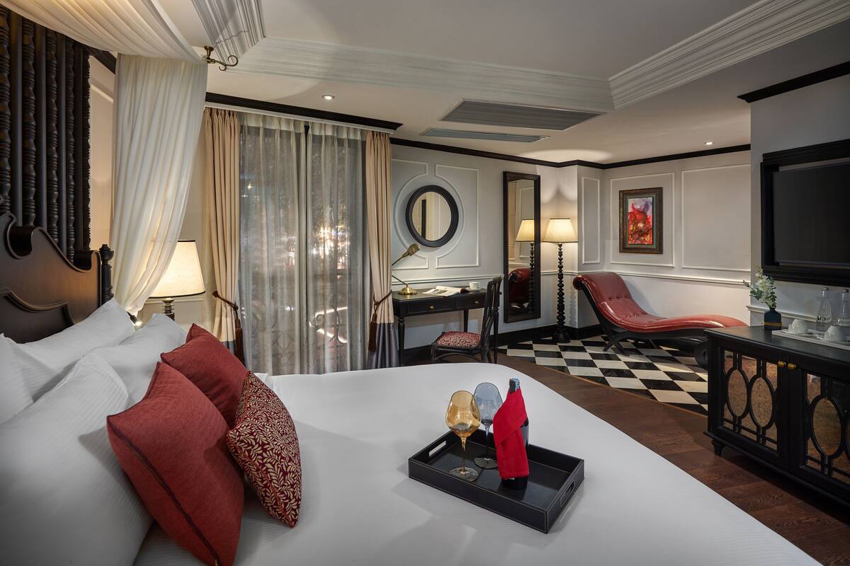 A hotel room with a large bed, a desk, a chair, and a TV.