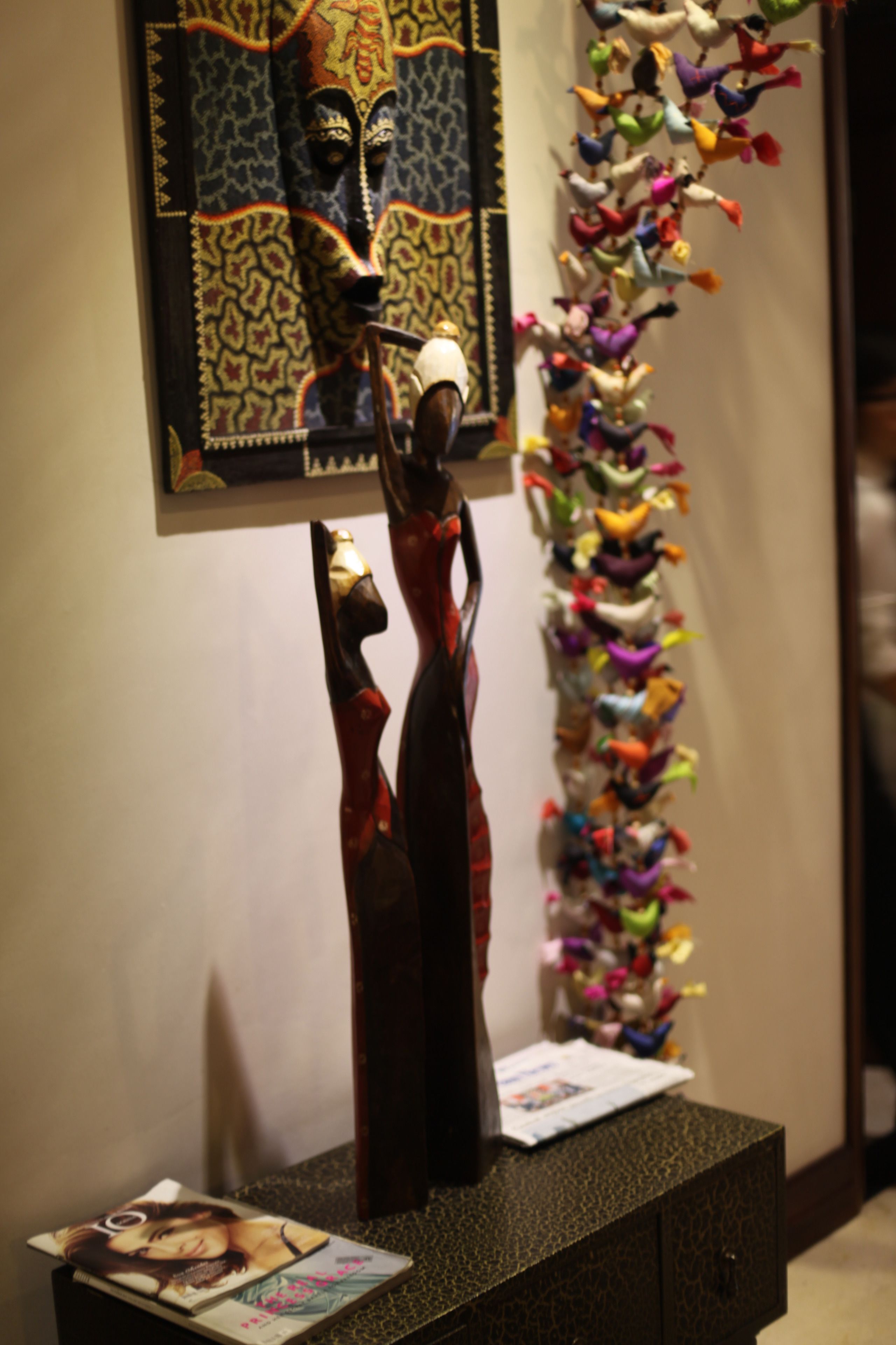 Uma receção com revistas, uma escultura decorativa e um painel de parede colorido.