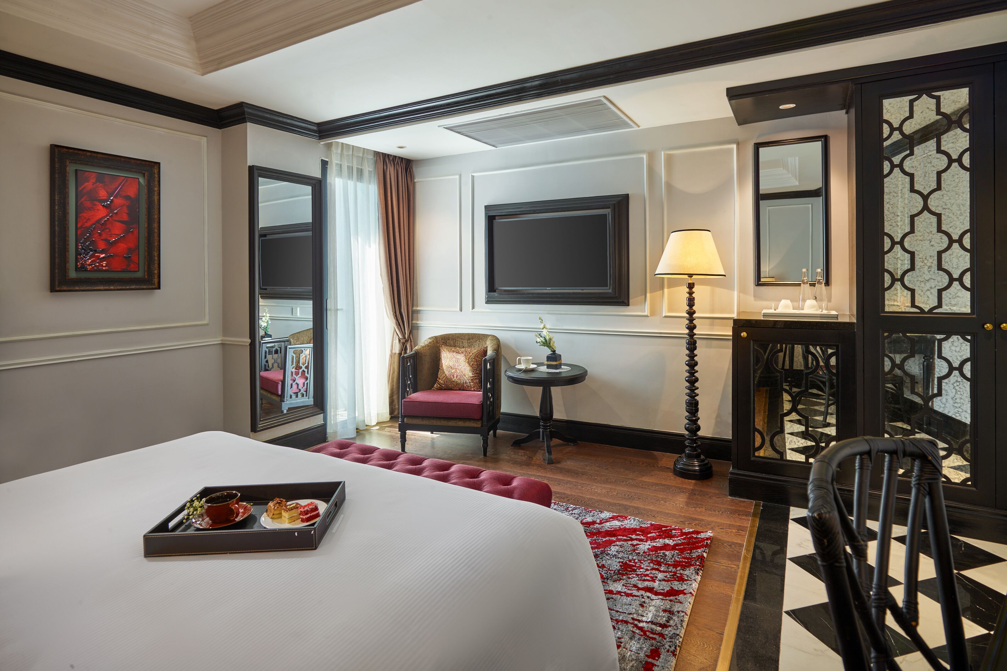 Une chambre d’hôtel avec un grand lit, une petite table avec une lampe, une chaise et un plateau avec de la nourriture.