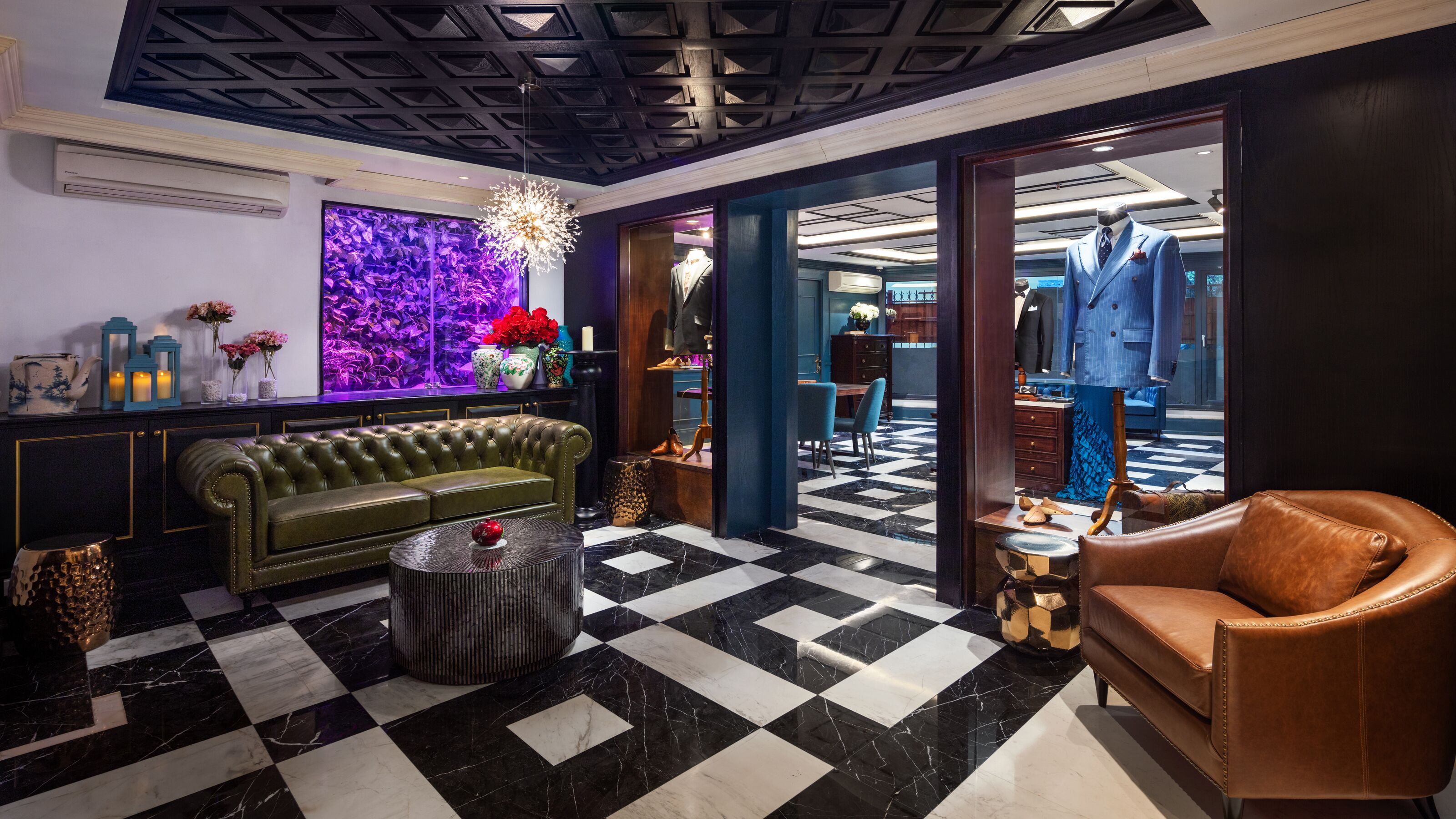 A lobby with a checkered floor, a green sofa, a brown leather armchair, and a bar area with a mannequin in a suit.