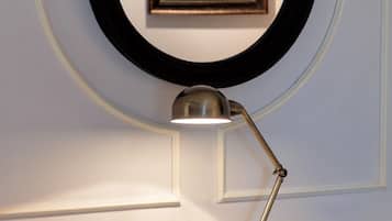 A desk with a book, a clock, a lamp, and a cup.