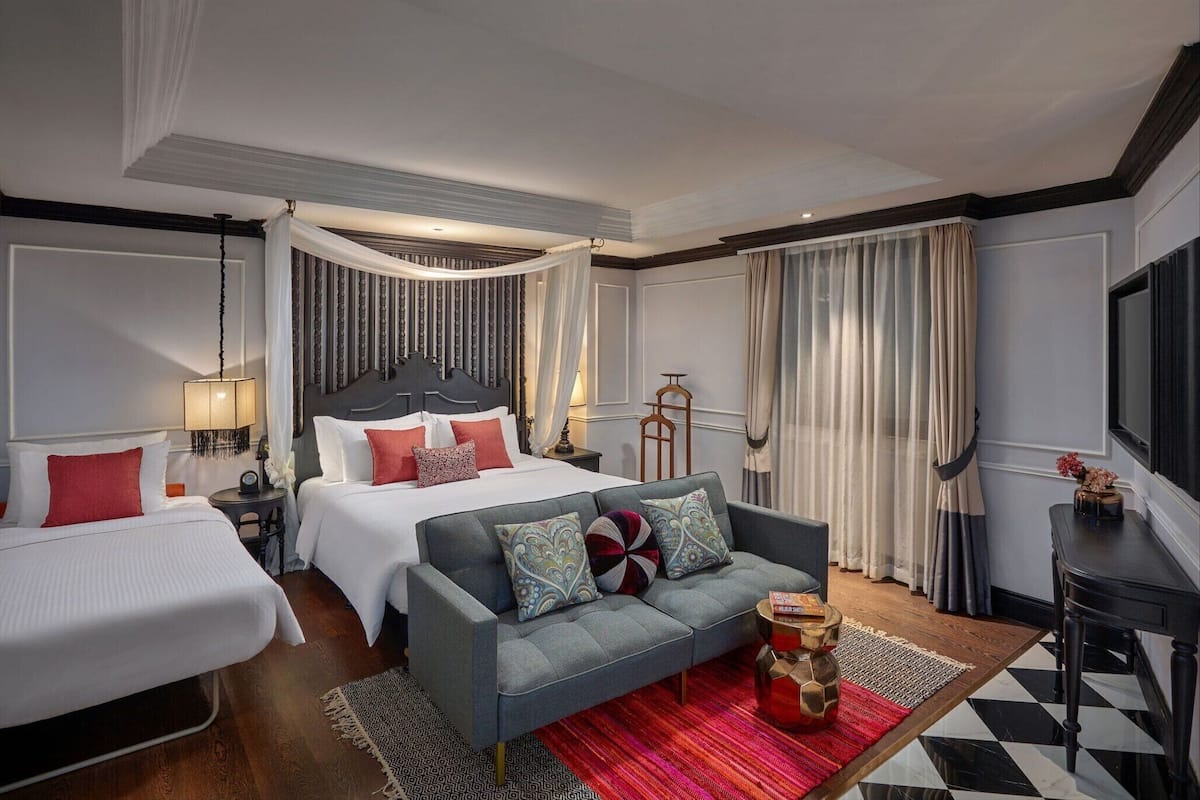 A hotel room with a bed, two sofas, a coffee table, and a TV.