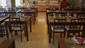 Un restaurante con varias mesas y sillas, una pared de mármol y un televisor fijado en la pared.