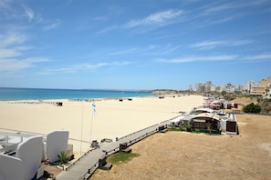A beachside hotel with a wooden deck, beach chairs, and umbrellas. - Hotel Santa Catarina Algarve (Portimão)