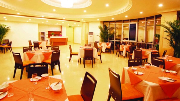 A spacious restaurant with multiple tables and chairs, a reception desk, and large windows allowing natural light. - Ane Hotel - Eying Branch (Chengdu)