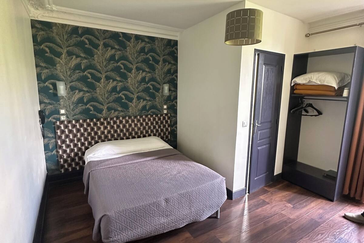 A bedroom with two beds, a wardrobe, and a hanging light fixture.