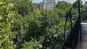 Blick auf ein mehrgeschossiges Gebäude mit heller Fassade, umgeben von üppigem Grün.